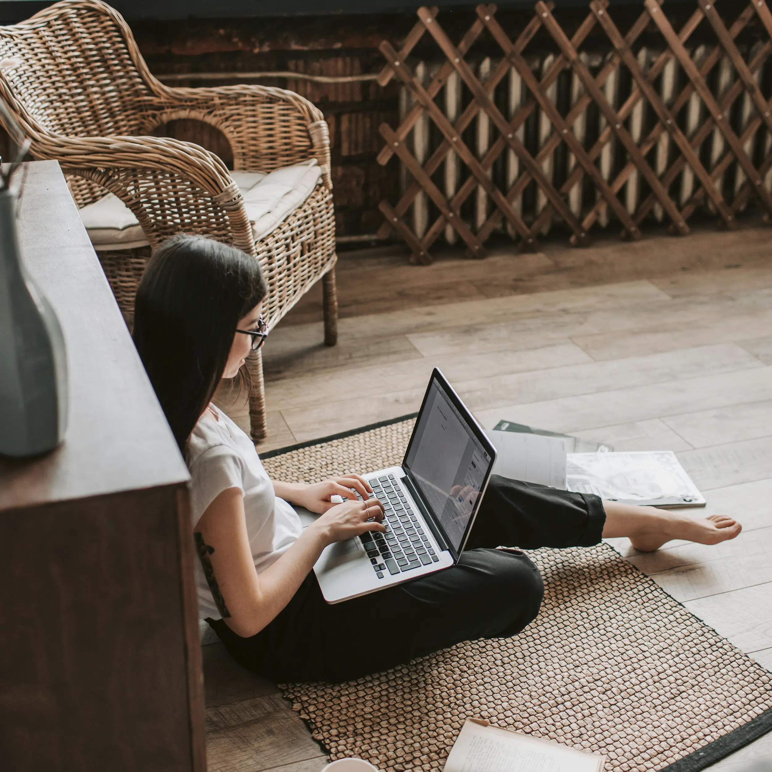 Juriste travaillant sur un ordinateur portable avec des documents juridiques autour d'elle dans un espace de travail confortable.