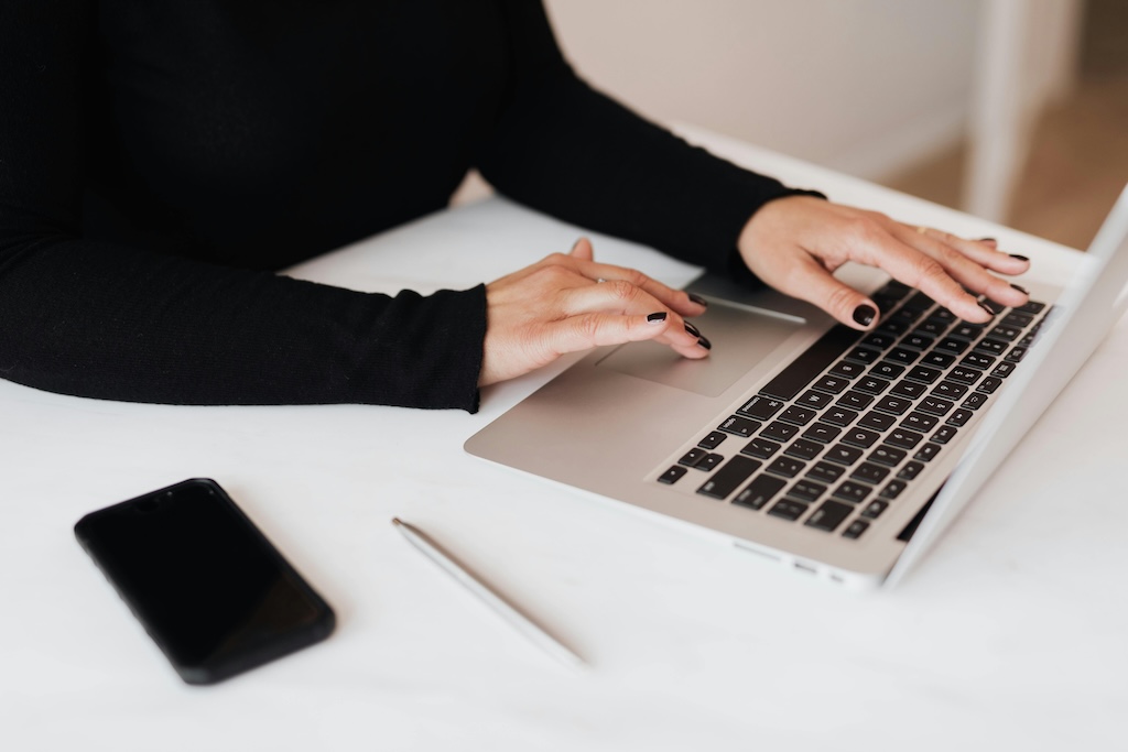 Jeune femme tapant sur son ordinateur, illustrant la différence CGV CGU dans la gestion juridique des ventes et de l’utilisation d’un site web.